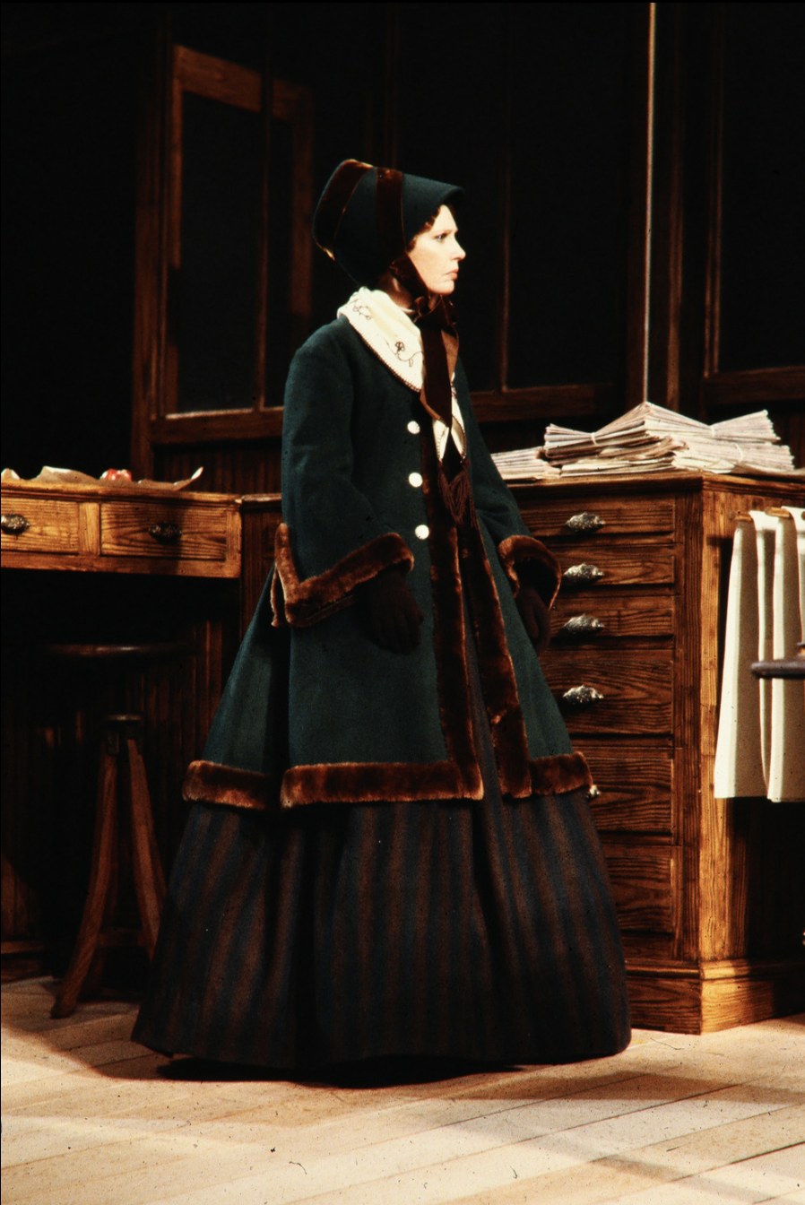 Woman in a dark fitted jacket and long skirt, An Enemy of the People, Seattle Repertory Theatre, costumes by Laura Crow